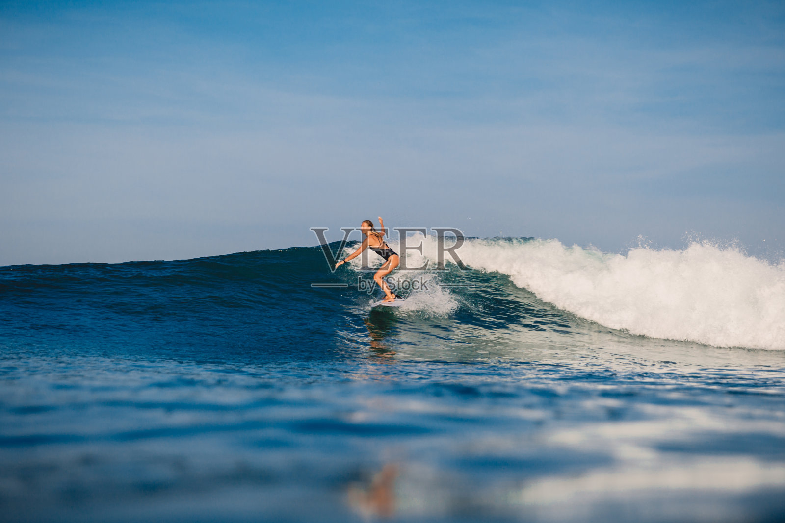 冲浪女子在冲浪板上乘风破浪。在晨光下冲浪的女人照片摄影图片