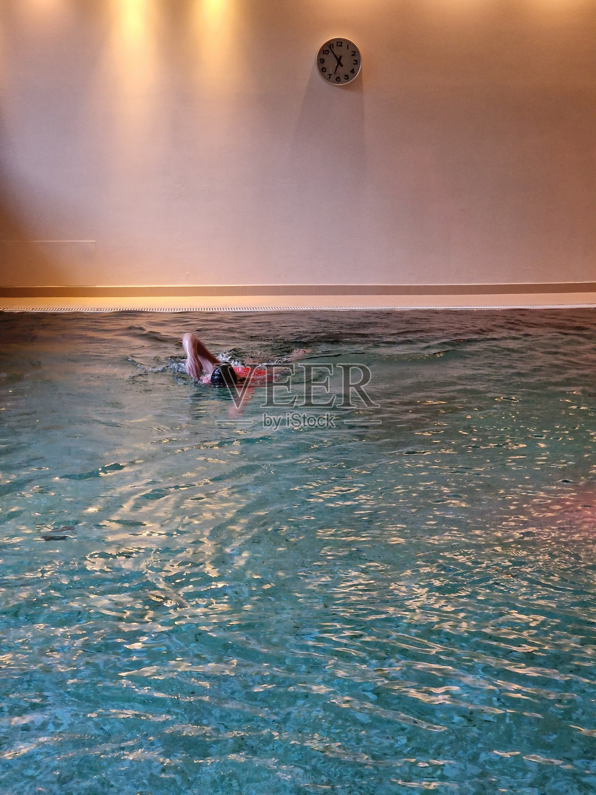 一个人戴着泳帽，在蓝色的游泳池里晨练游泳照片摄影图片