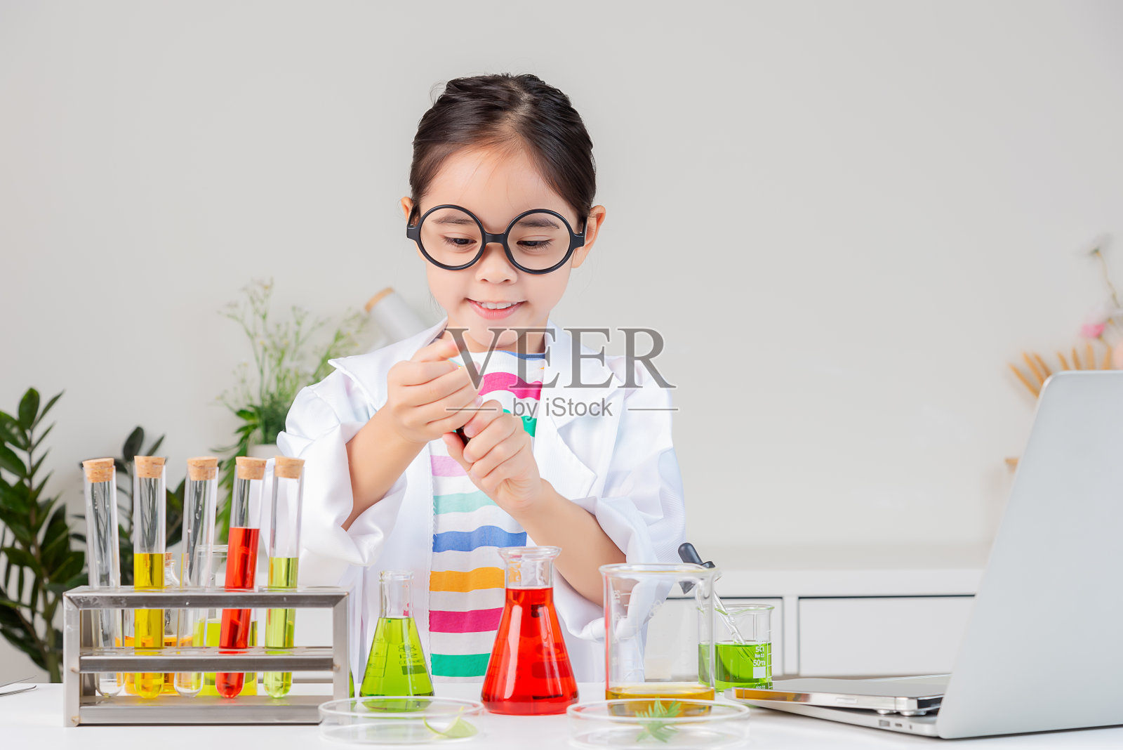 亚裔小女孩在白色教室里做试管科学实验照片摄影图片