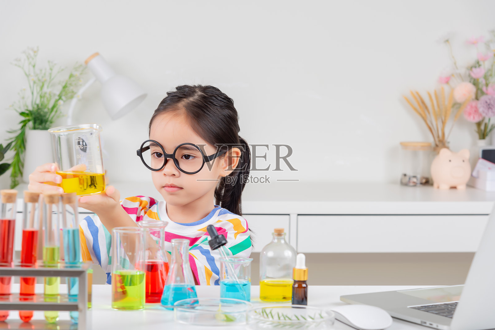 亚裔小女孩在白色教室里做试管科学实验照片摄影图片