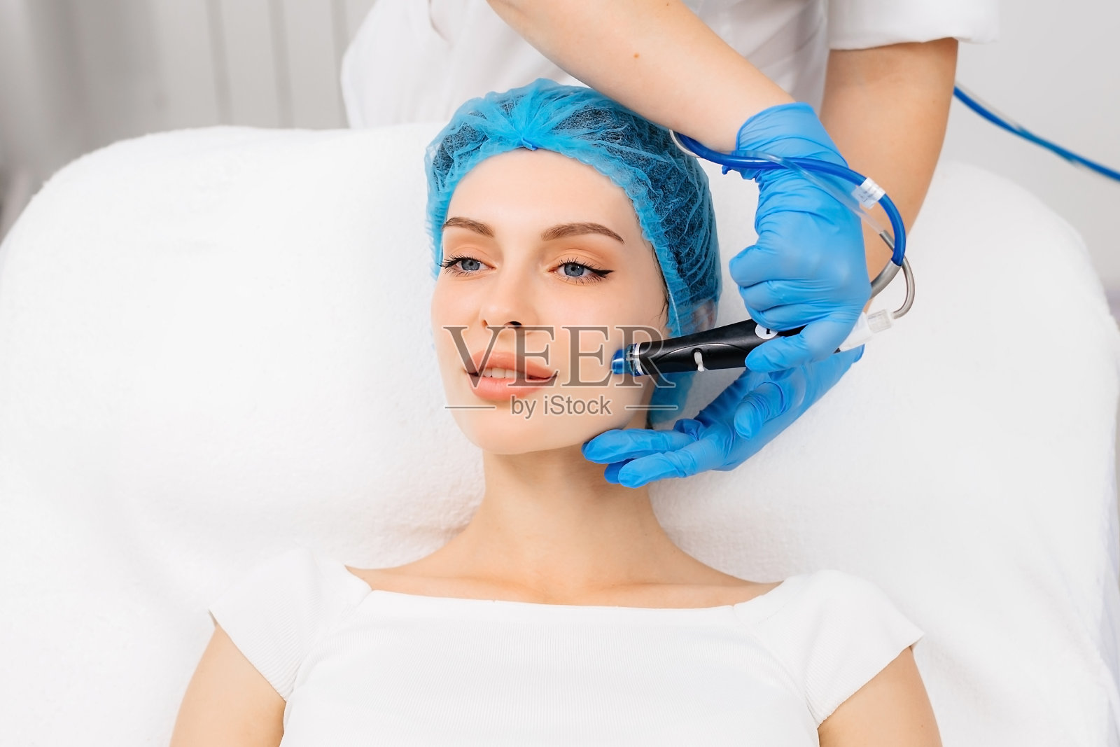 一位美丽的年轻女子在美容院的灯光背景下接受真空脱皮手术。照片摄影图片