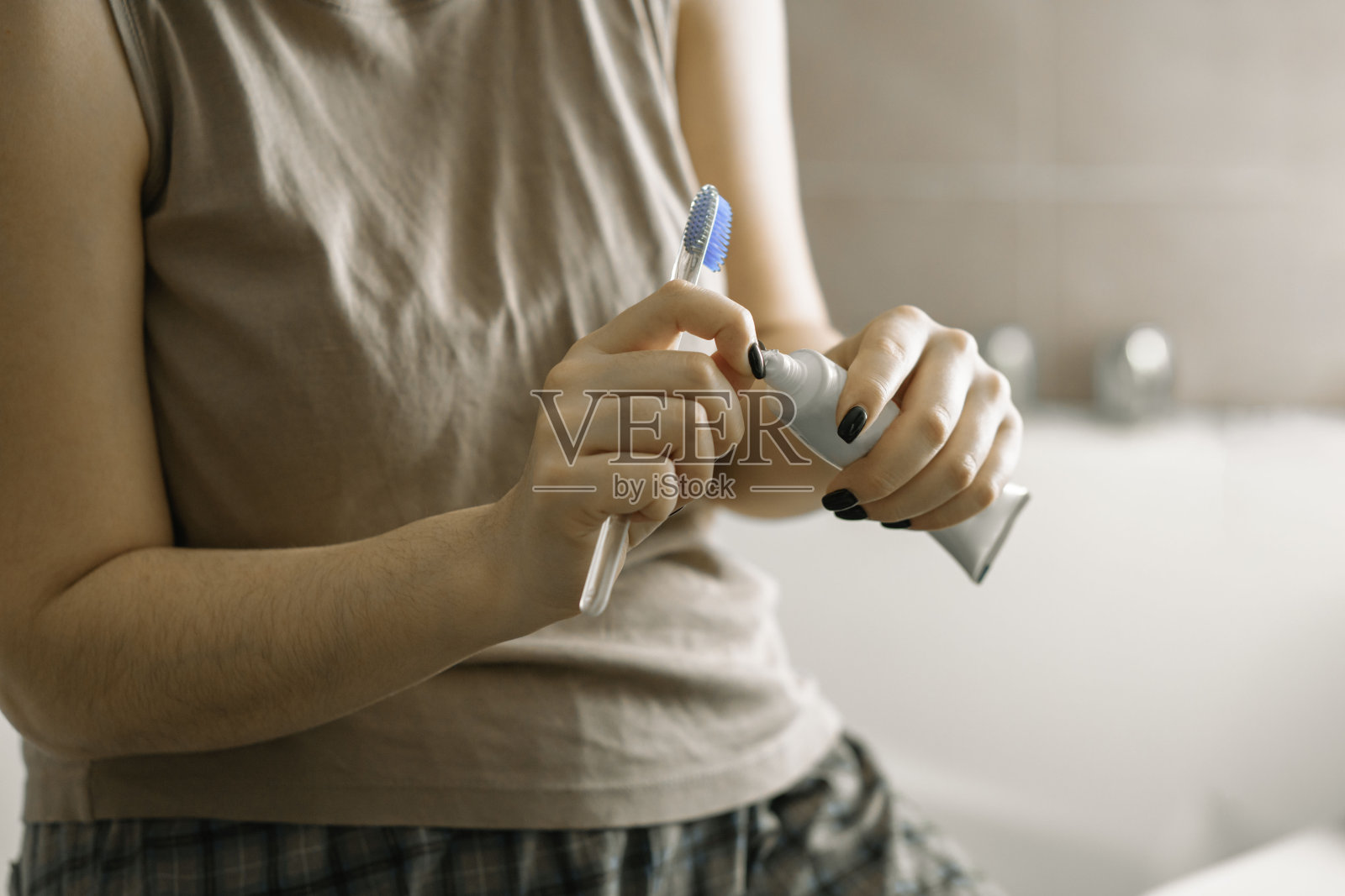 一个女人拿着牙刷，在浴室里取出牙膏的特写镜头照片摄影图片