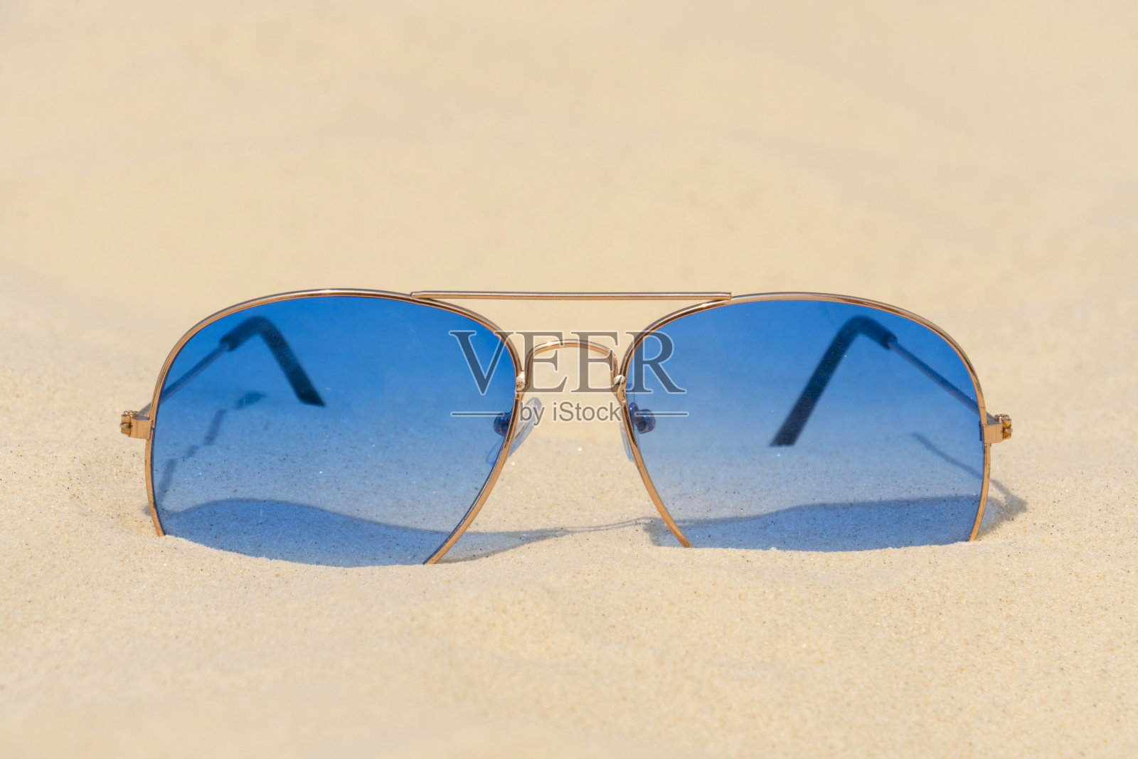 蓝色的太阳镜躺在沙滩上照片摄影图片