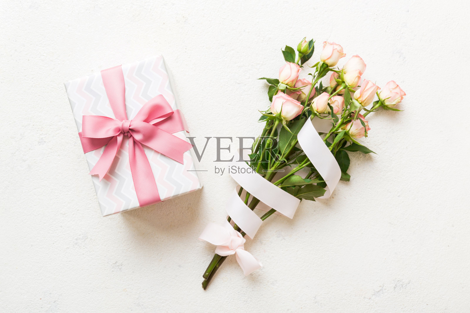 设计概念与粉红色的玫瑰花和礼盒在彩色的桌子背景顶视图。节日快乐，母亲节，生日概念。浪漫平铺构图照片摄影图片