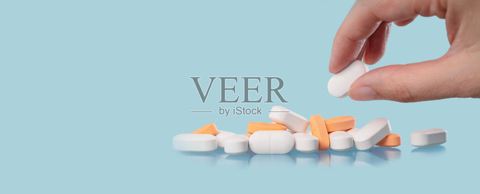 手和蓝色桌子上的白色药片，医药照片摄影图片