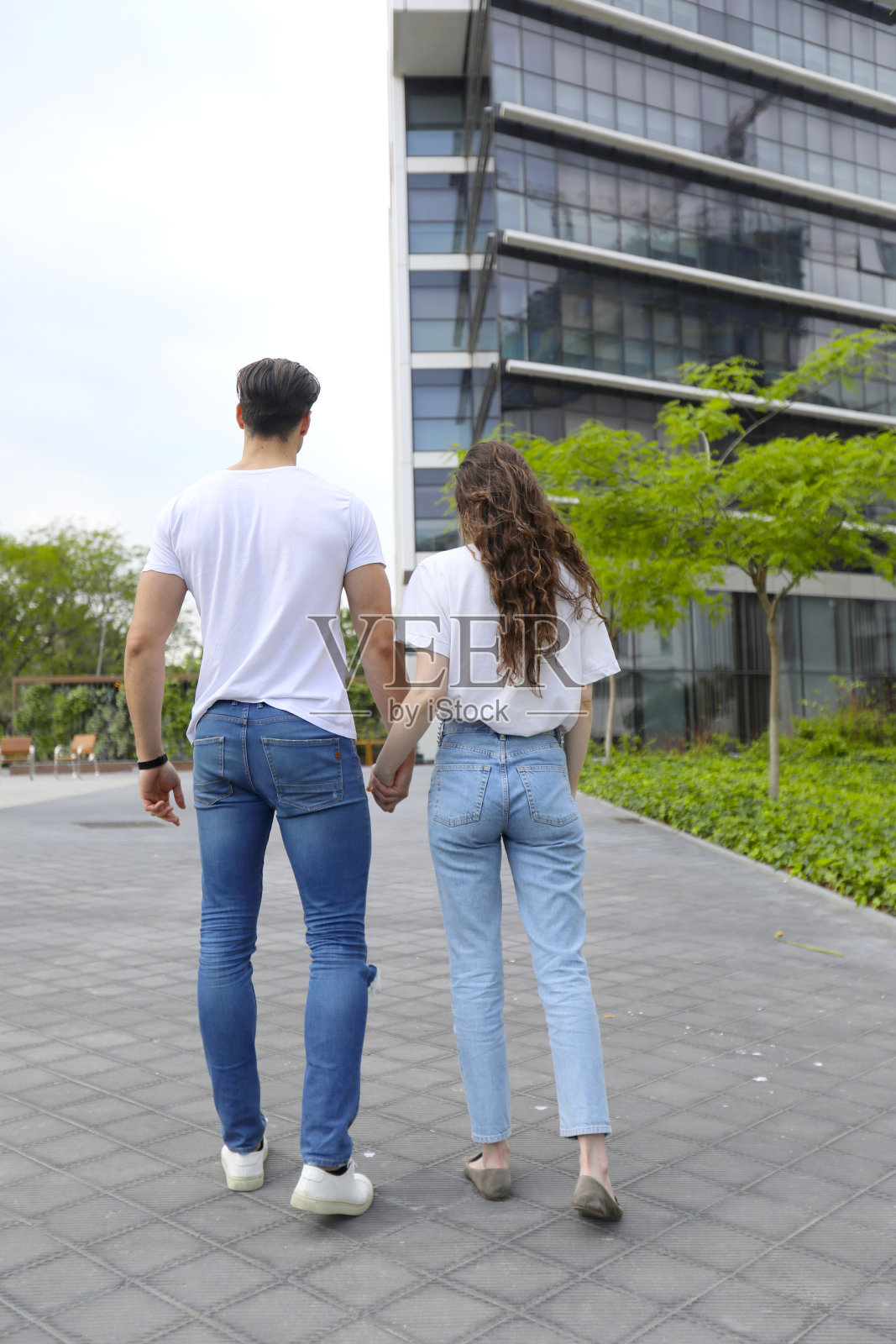 一对年轻夫妇手牵着手走在城市街道上的后景照片摄影图片