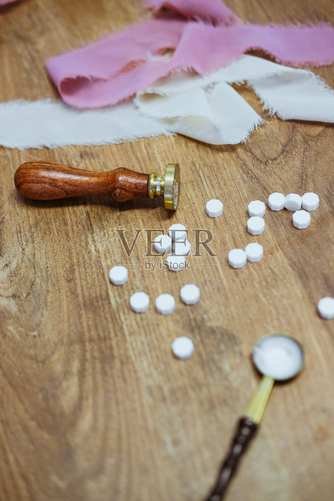 一张木桌上放着一张老式的蜡封邮票。金汤匙和几块蜡照片摄影图片