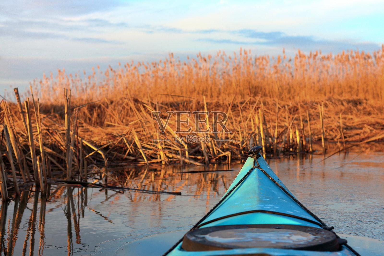 冬季或初春河流中漂浮在浮冰中的蓝色皮艇的船首。冬天皮划艇照片摄影图片