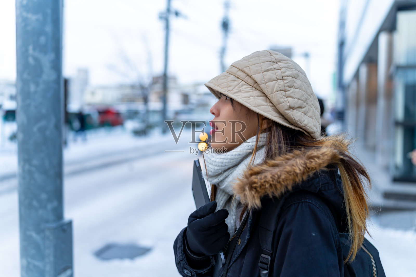 一名亚洲女子在冬夜的城市里散步时，戴着耳机听着音乐。照片摄影图片