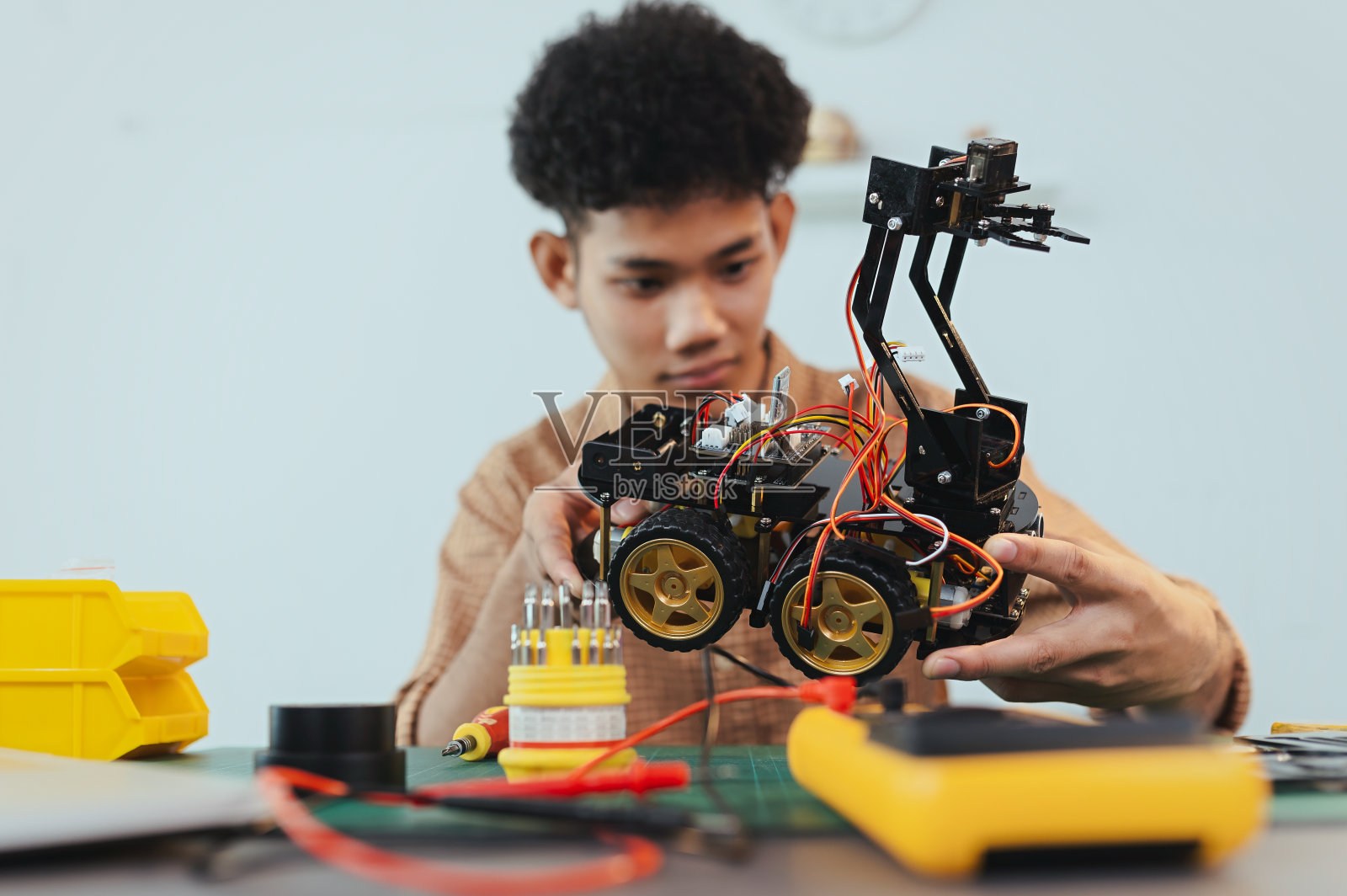 亚洲年轻人组装机器人汽车，专注于机器人技术，组装机器人机器人开发智能机器人，机械系学生组装救援机器人汽车。监视机器人。照片摄影图片