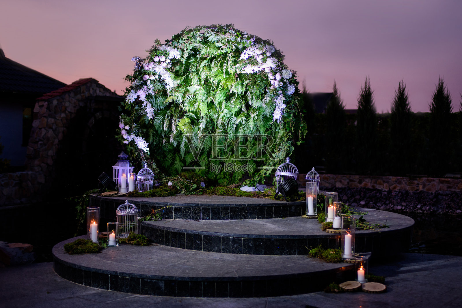 晚上用蕨类植物和蜡烛装饰的婚礼拱门。照片摄影图片