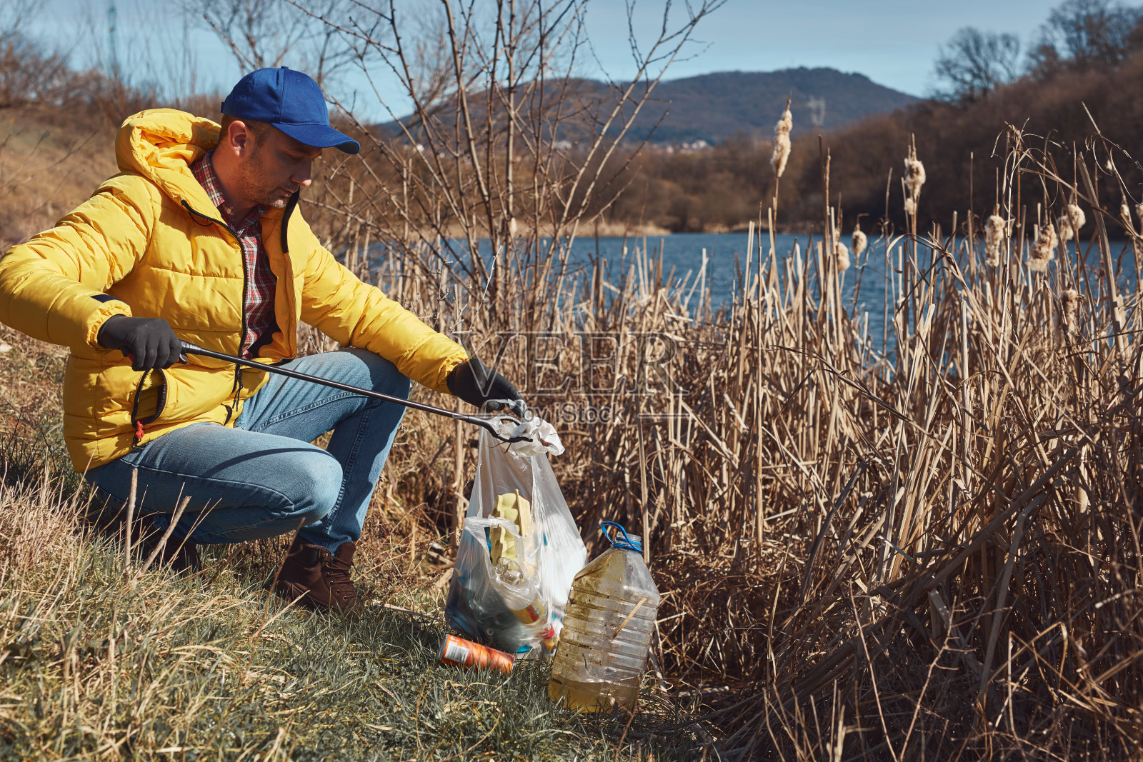 志愿者和环保人士正在清理堆满垃圾的脏湖岸。照片摄影图片