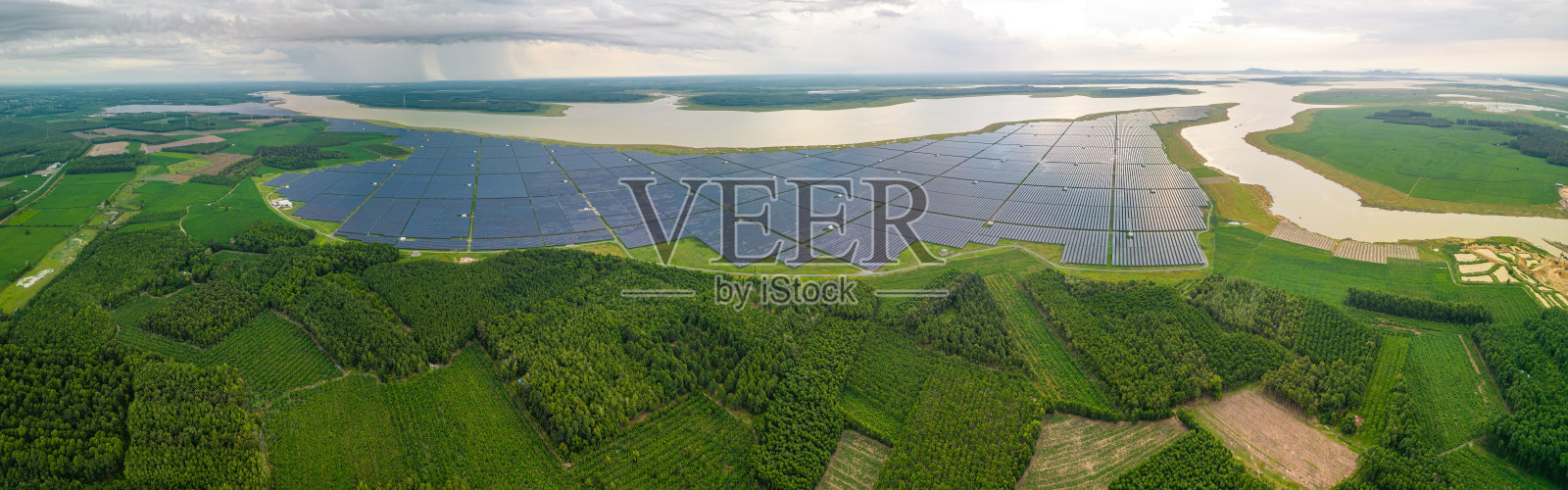 鸟瞰大型可持续发电厂，多排太阳能光伏板，在多云的农村，越南Tay Ninh照片摄影图片