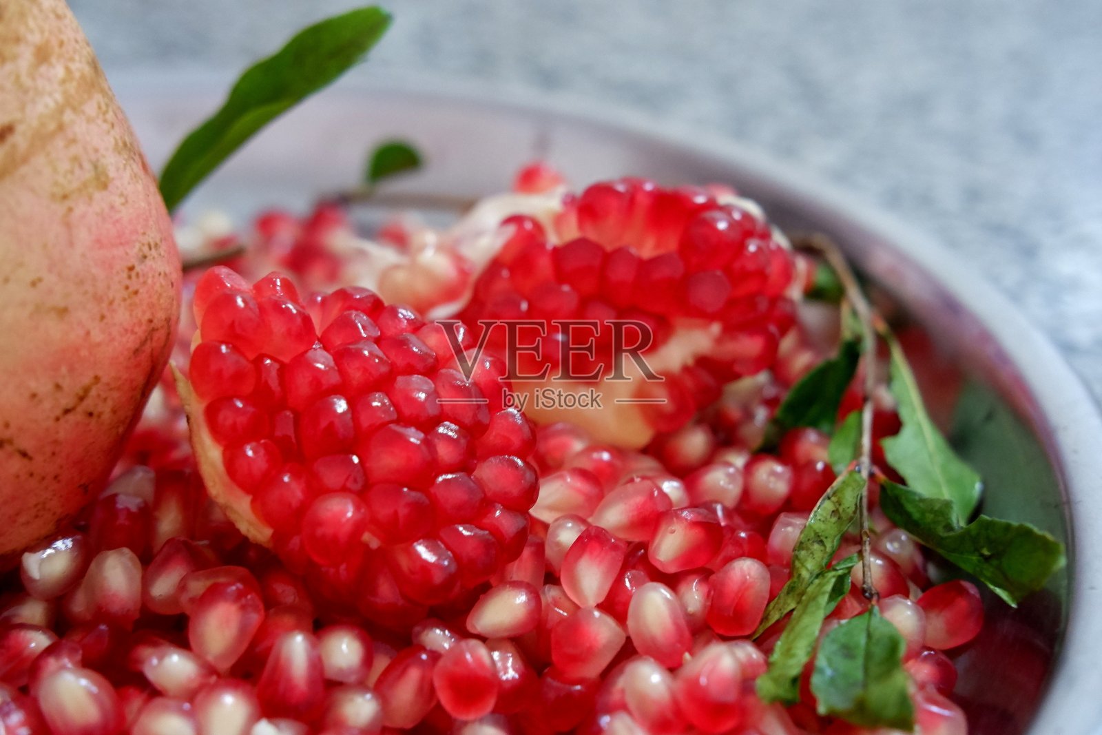 厨房桌子上托盘里的多汁石榴果实和种子照片摄影图片