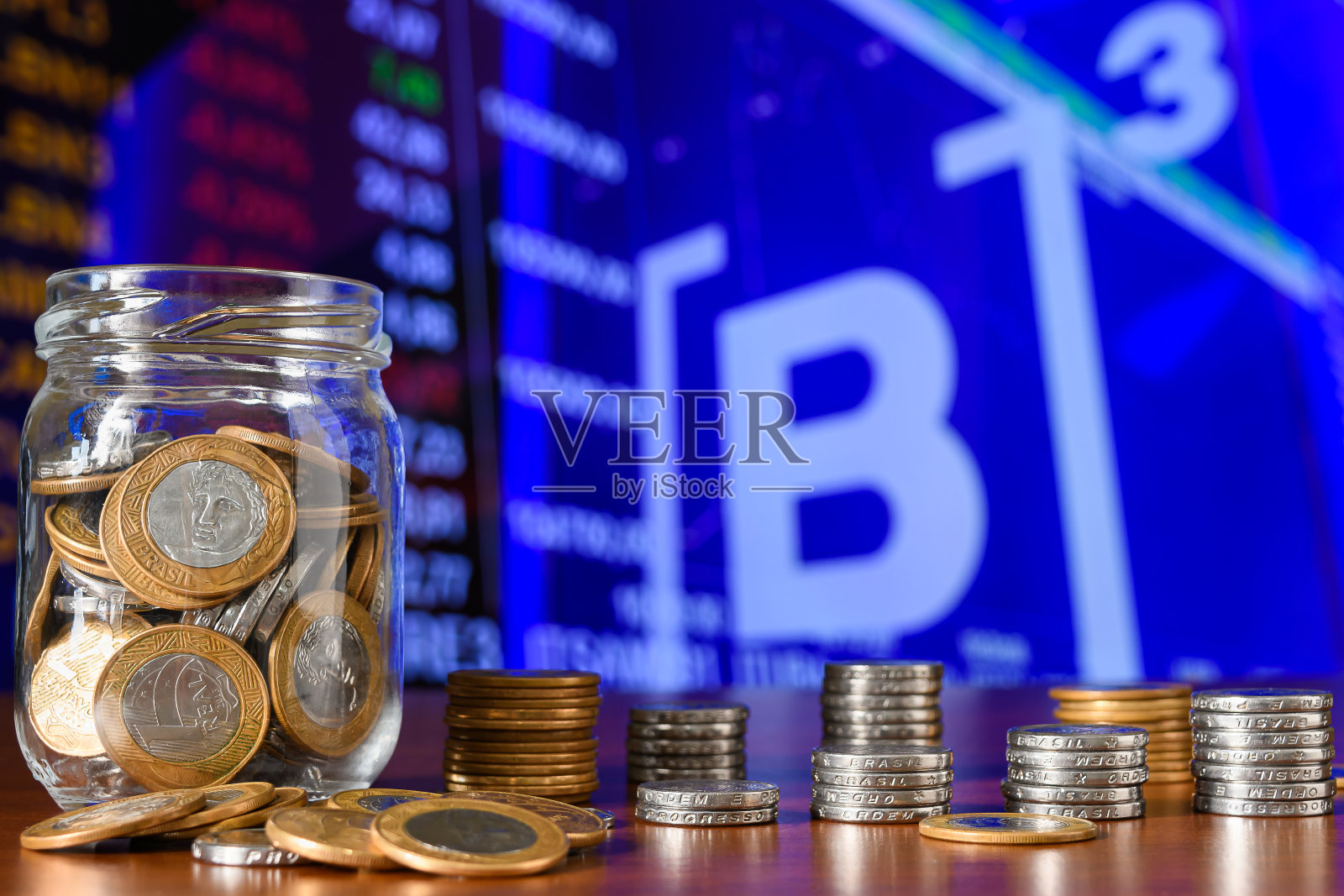 证券交易所背景上的玻璃罐里的硬币照片摄影图片