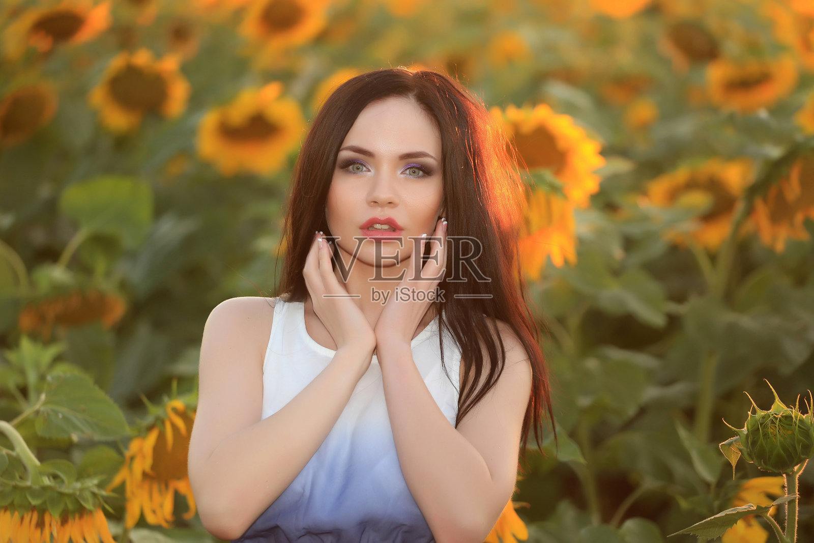 一个漂亮时髦的红头发女孩站在油菜籽地里，穿着裙子，背景是黄色的花朵照片摄影图片