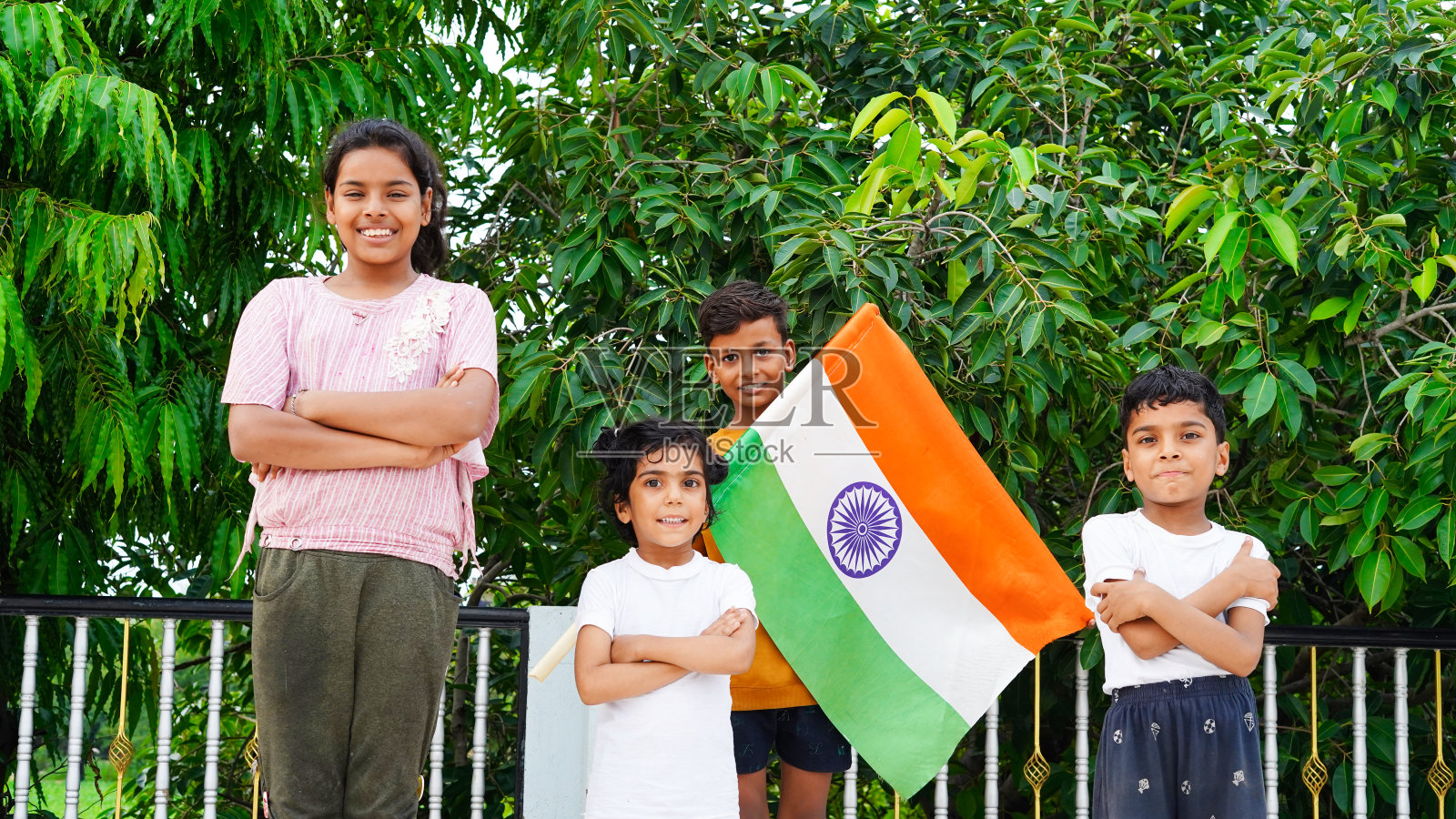 孩子们站在阳台上，展示着印度国旗，看着镜头。庆祝独立或共和国日的孩子照片摄影图片