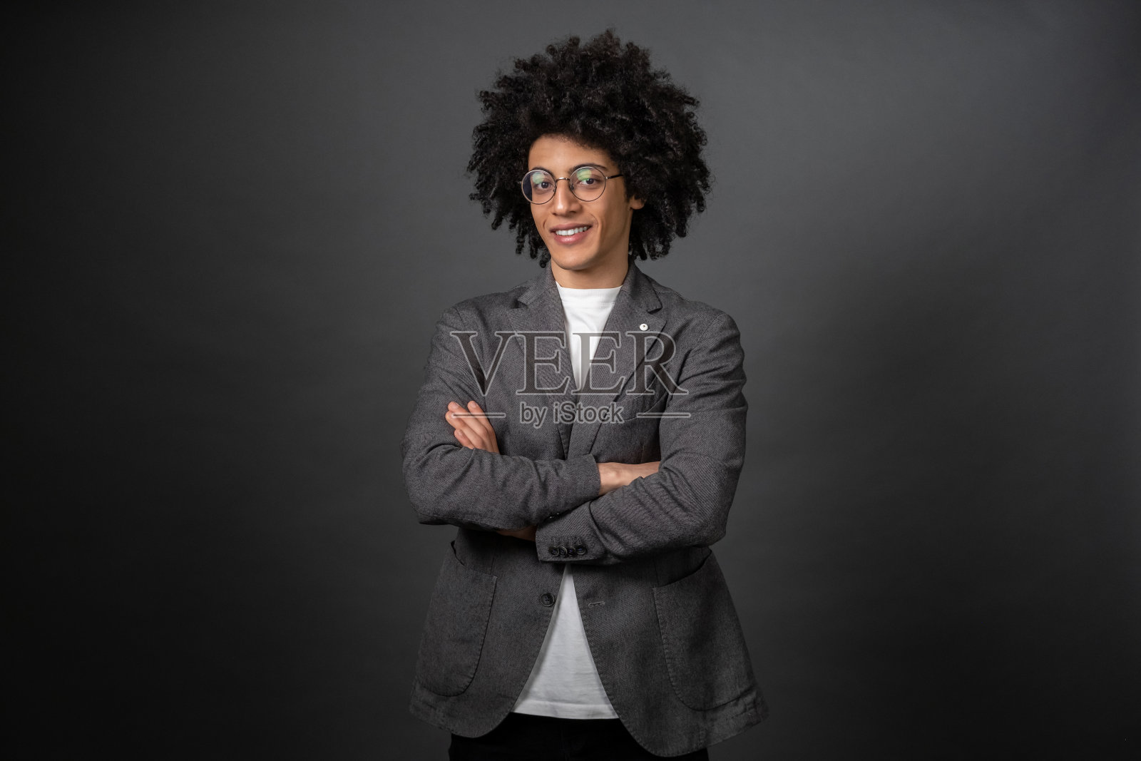 一头卷发的年轻商人双臂交叉站着照片摄影图片