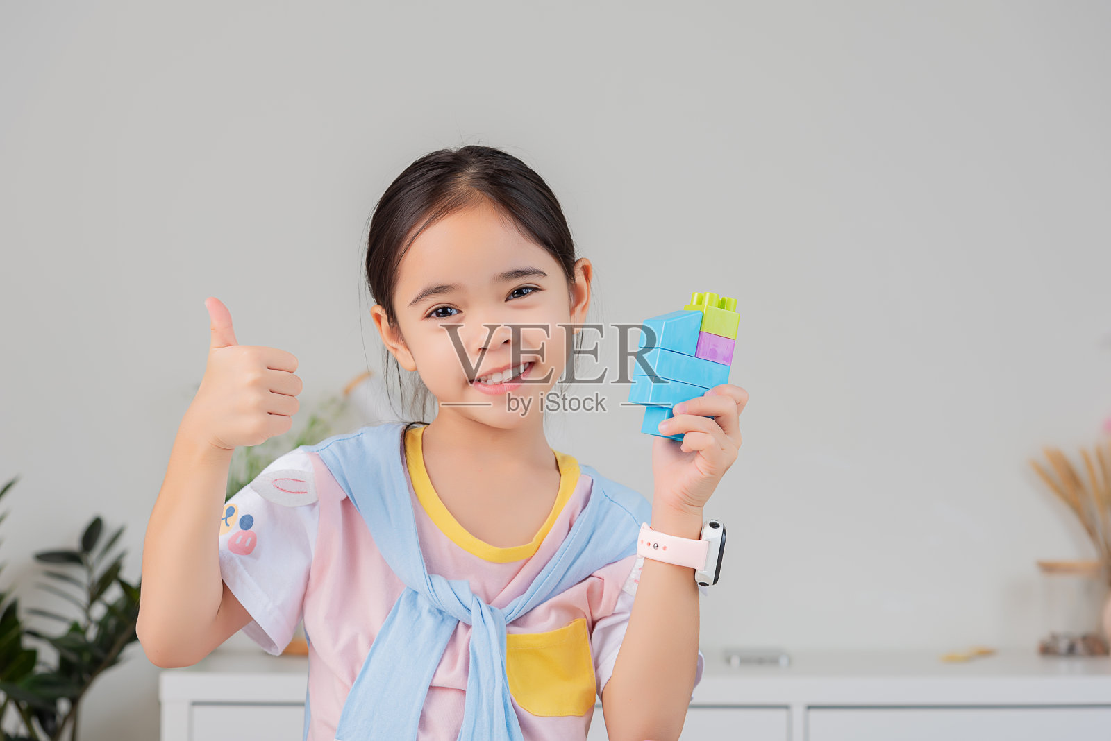 小女孩正在玩五颜六色的积木拼图。在白色的房间里照片摄影图片