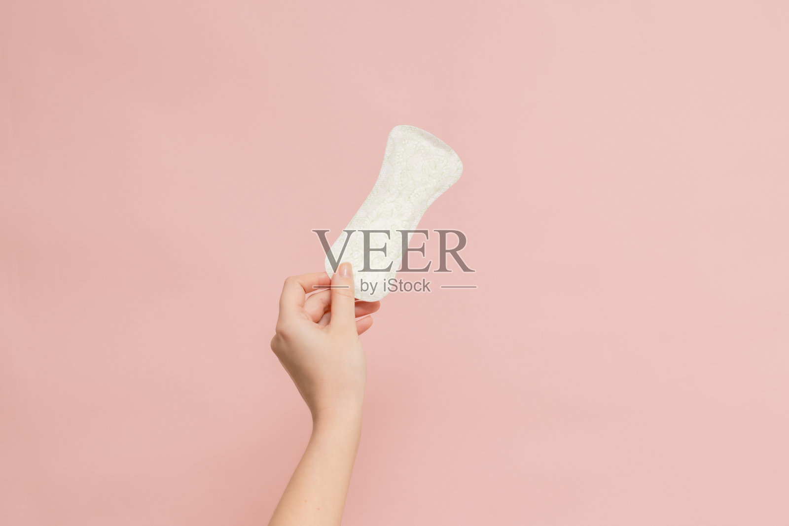 女人手拿卫生巾在粉红色的背景照片摄影图片