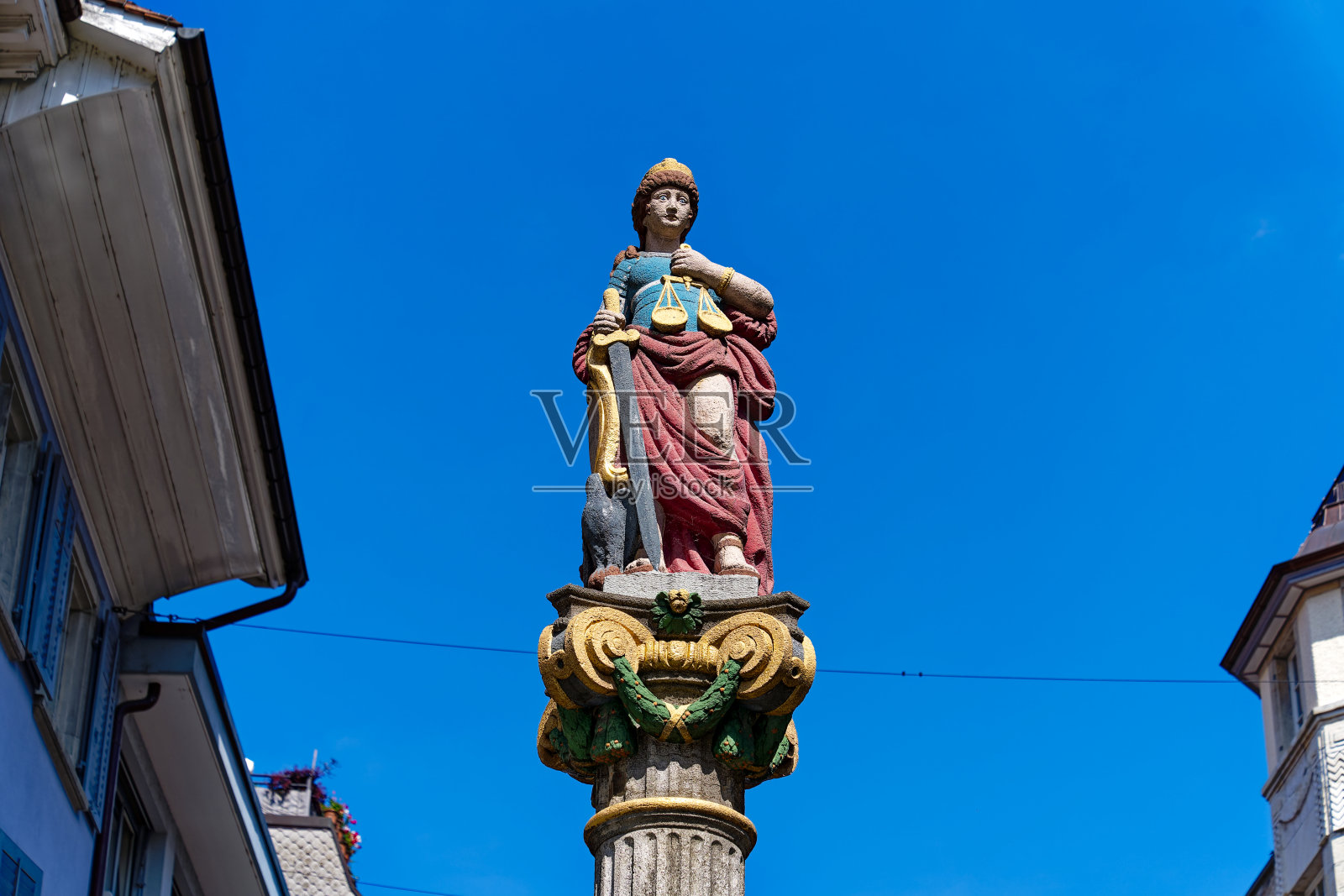 仰望1979年1月25日在瑞士小镇历史街区以蓝天为背景竖立的喷泉雕像。照片摄影图片