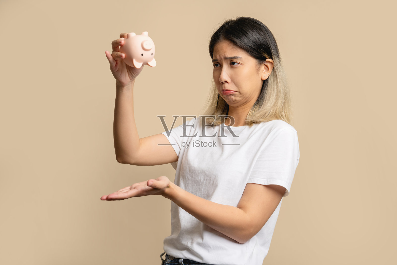 悲伤和失望的美丽的亚洲女人拿着一个没有钱的储蓄罐。照片摄影图片