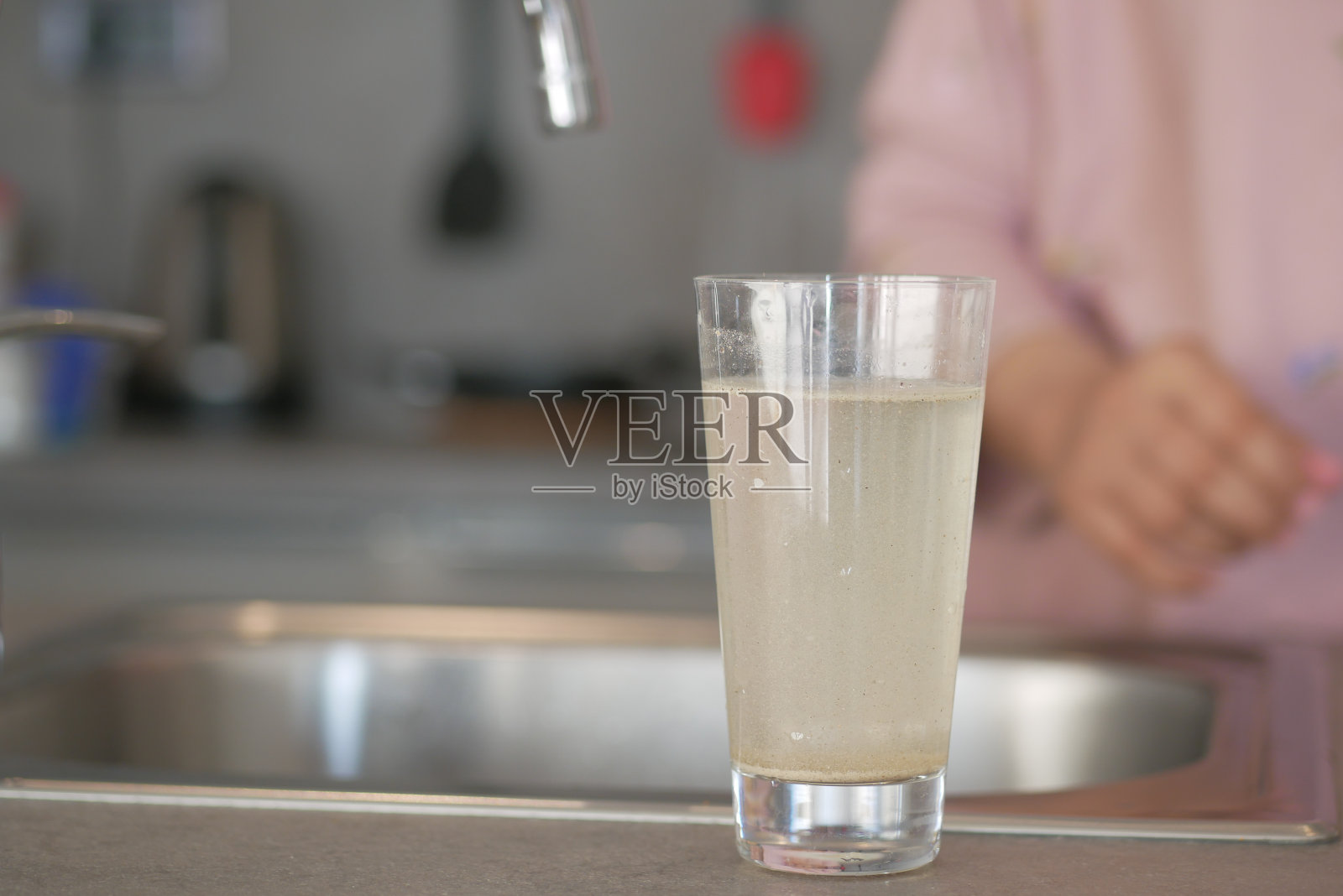 脏水从水龙头里从玻璃杯里流出，照片摄影图片