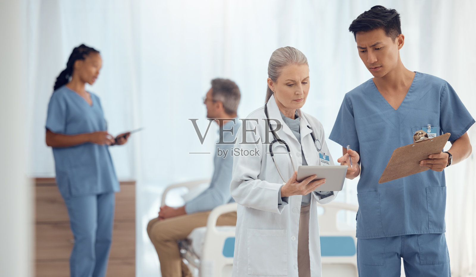 团队合作，安排医生与平板或检查表在医院开会或讨论合作。结果，外科医生或护士谈论或谈到医疗保健研究，报告数据或新闻照片摄影图片