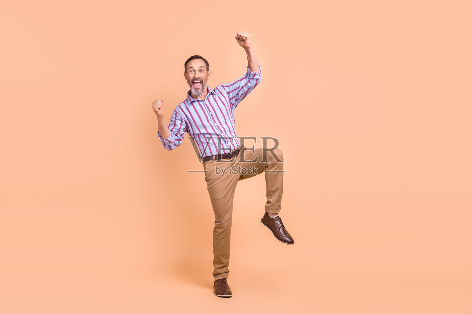 在米色的背景上，高高兴兴的银行家男子举起拳头凯旋，空出一片空间照片摄影图片