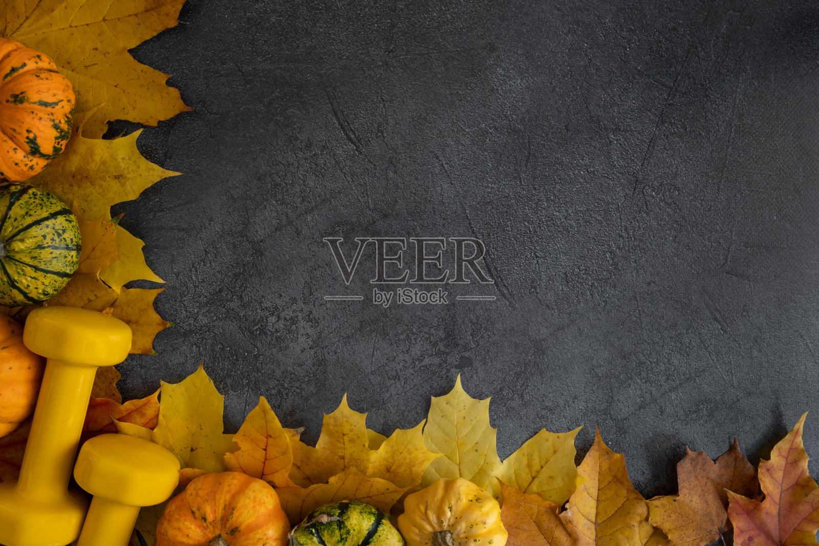 健身房的哑铃，装饰南瓜和秋叶。健康健身的生活方式与文案空间平铺构成。照片摄影图片