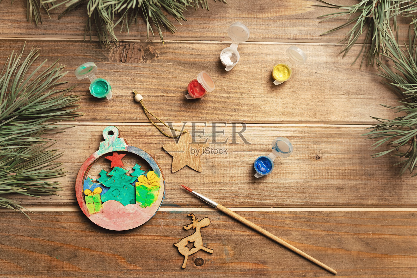 在旧桌子上用画笔和颜料装饰圣诞树的木制玩具照片摄影图片