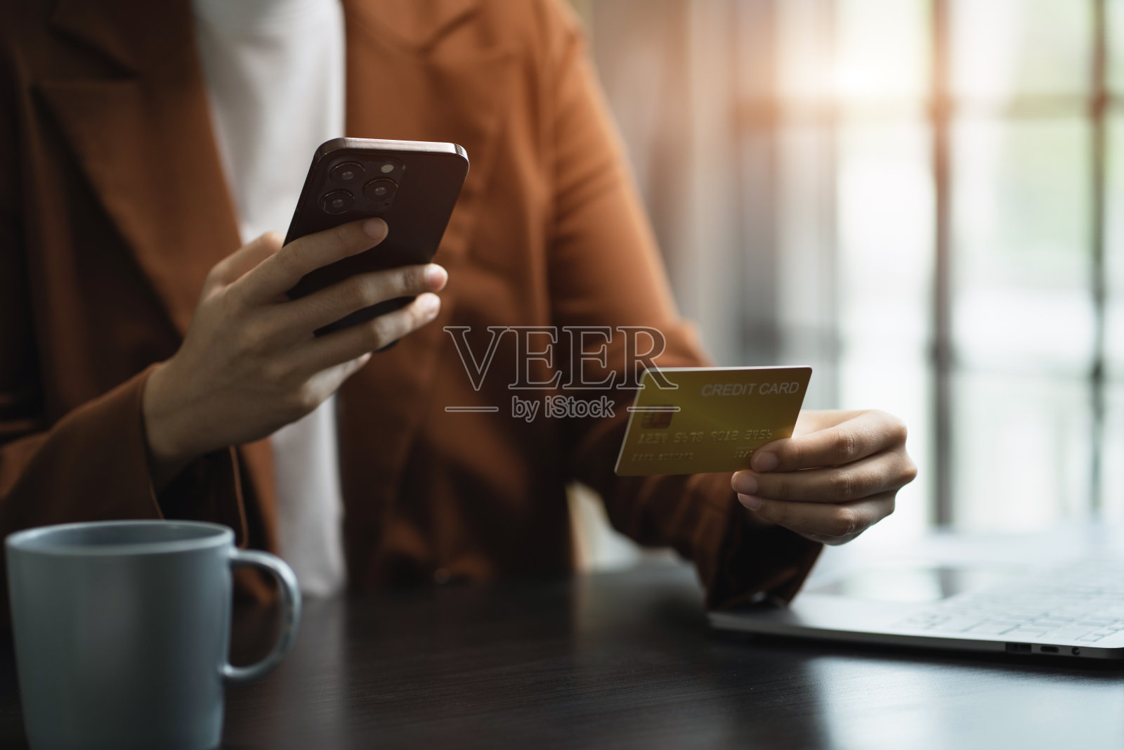 特写女性手持信用卡。商人在早上使用智能手机在线支付购物。照片摄影图片