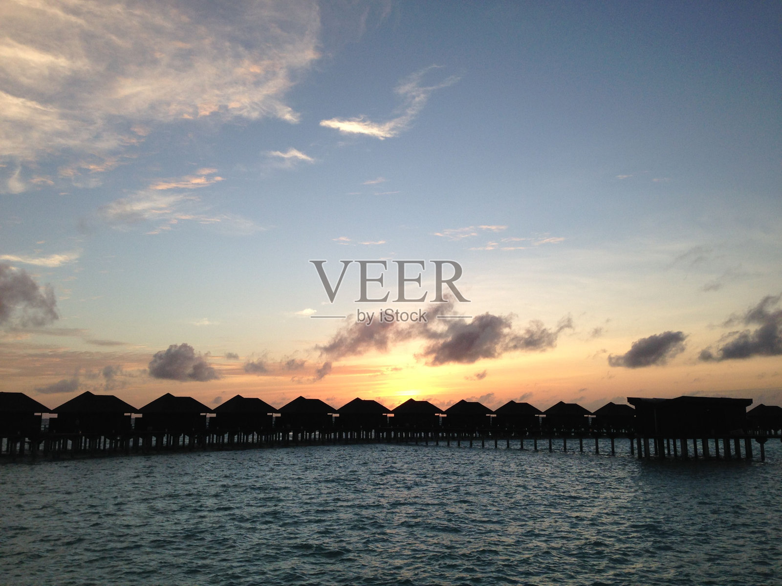 阳光明媚的早晨，码头上传统茅草屋顶小屋的剪影照片摄影图片