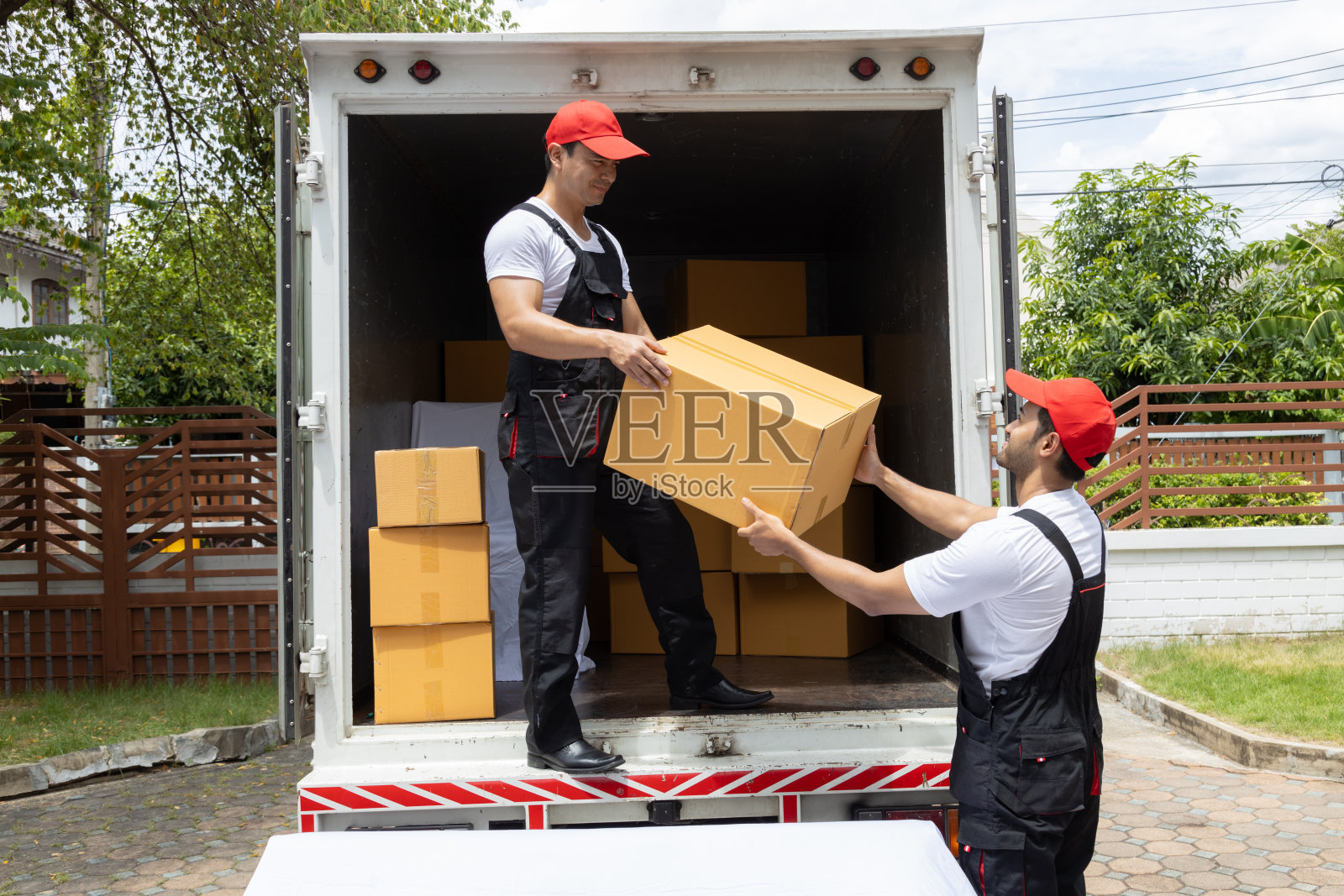 两名搬运工从一辆皮卡车上卸下箱子和家具。照片摄影图片