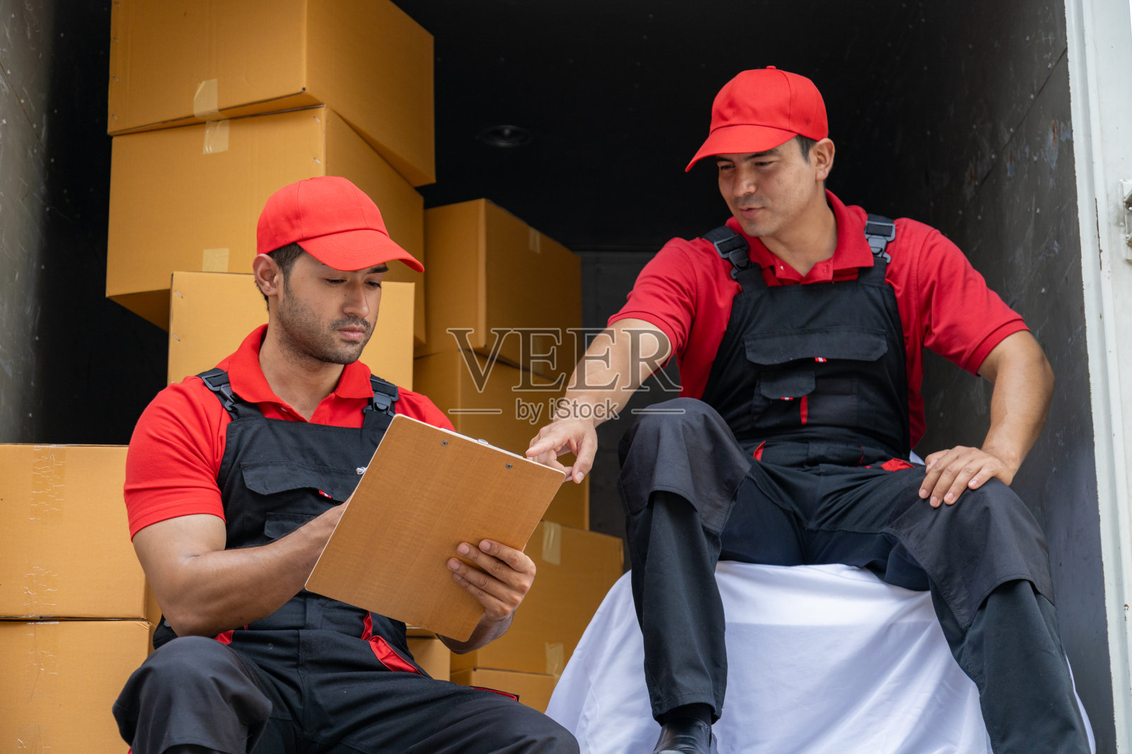 两名搬运工从一辆皮卡车上卸下箱子和家具。照片摄影图片