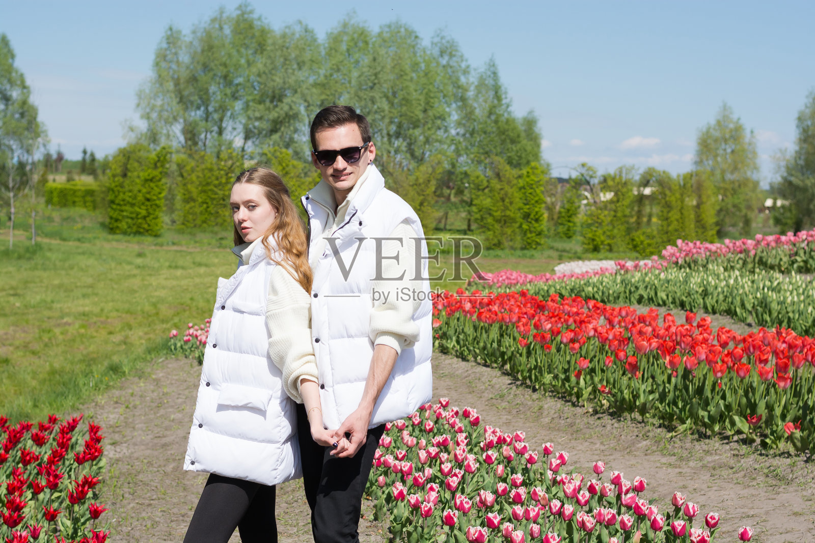 一对年轻美丽的微笑着的夫妇，背景是一片五颜六色的郁金香。照片摄影图片