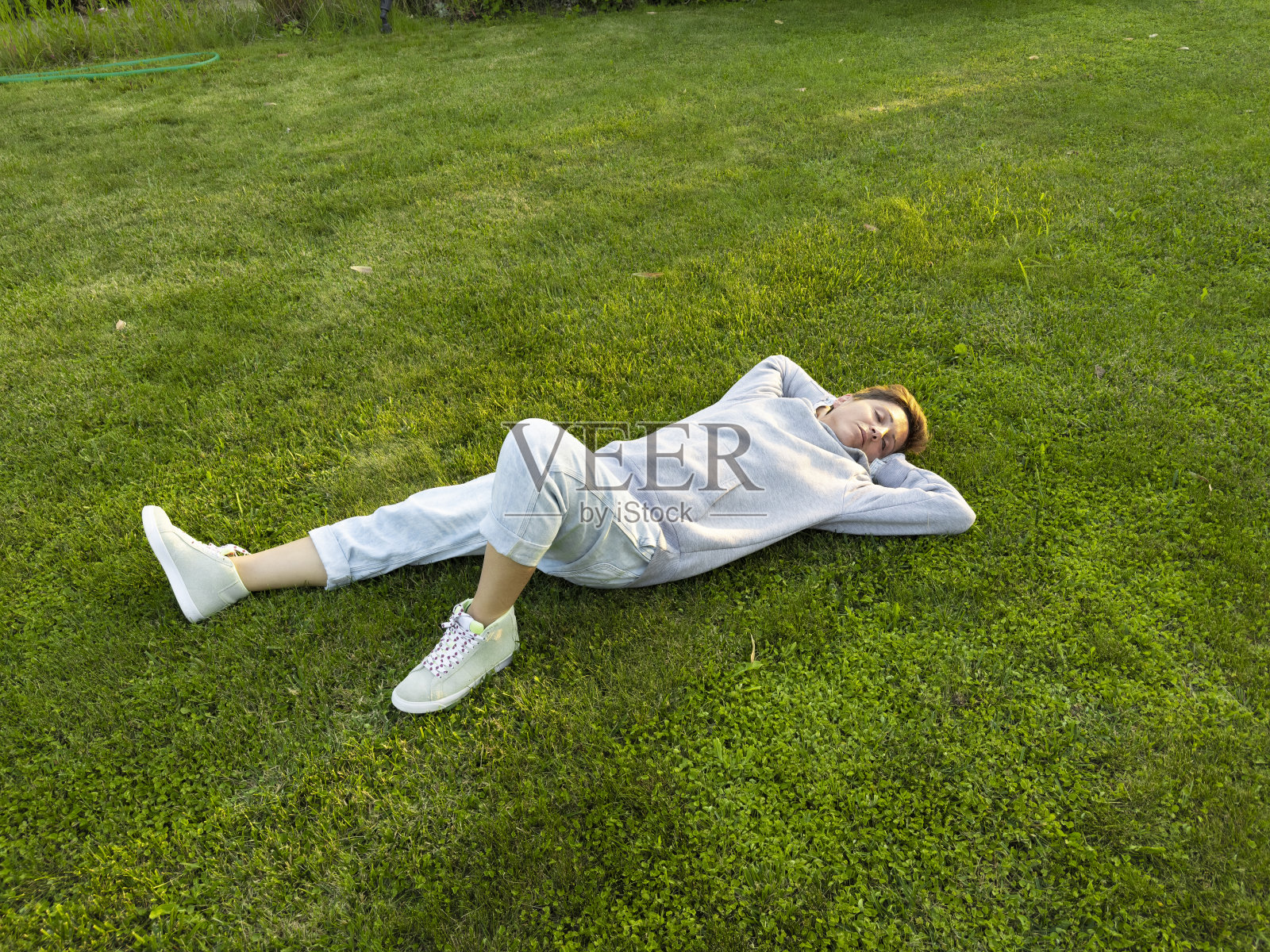 一个成年女人躺在草地上。照片摄影图片
