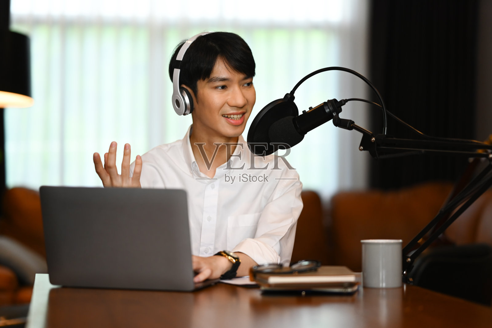 帅气的男电台主持人戴着耳机采访嘉宾，在家里的演播室录制播客照片摄影图片