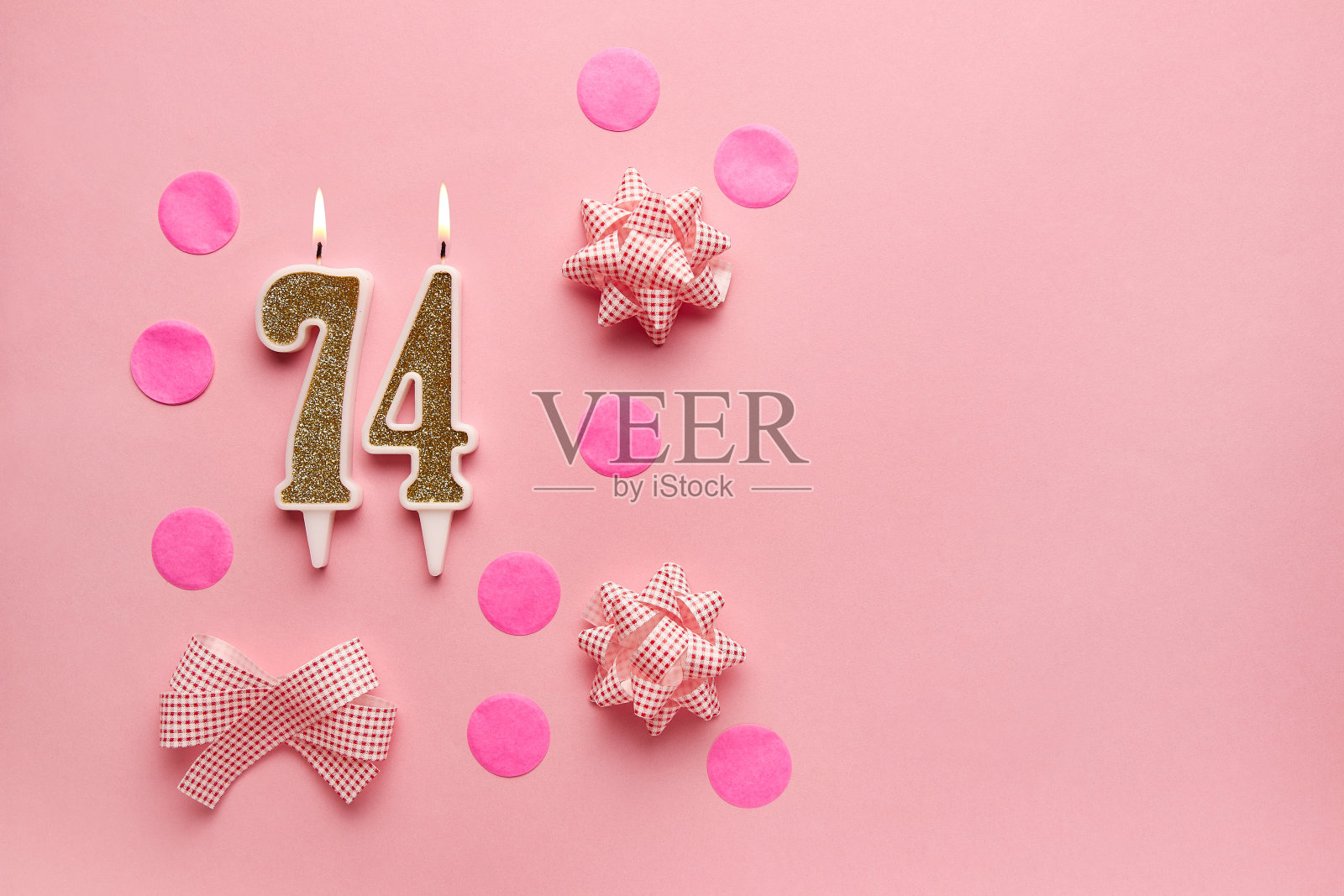 74号，淡粉色背景，节日装饰。生日快乐，蜡烛。庆祝生日、周年纪念、重要日期、节日的概念。副本的空间。横幅照片摄影图片