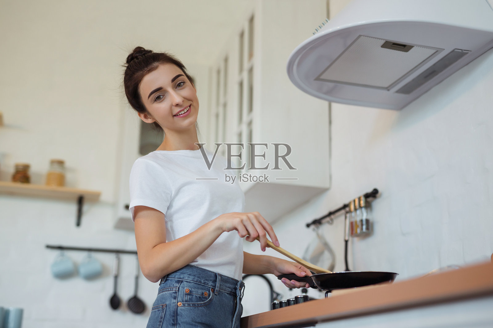 在现代阁楼式厨房用平底锅烹饪美食的快乐迷人年轻主妇照片摄影图片