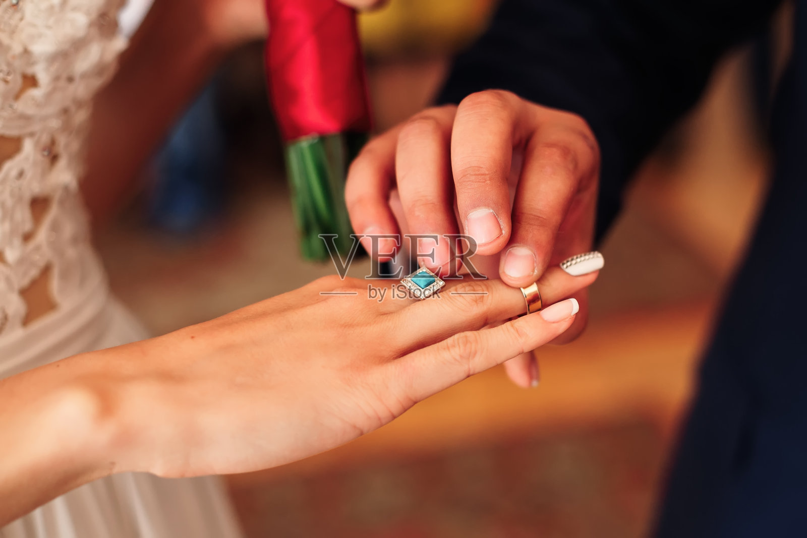 新郎把结婚戒指戴在新娘的手指上照片摄影图片