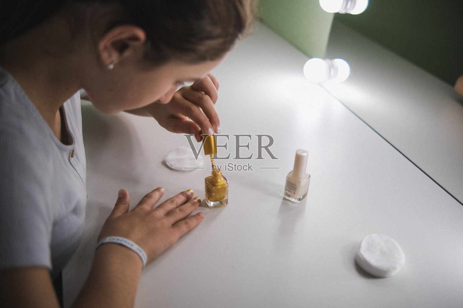 女孩在化妆间的镜子前涂指甲照片摄影图片