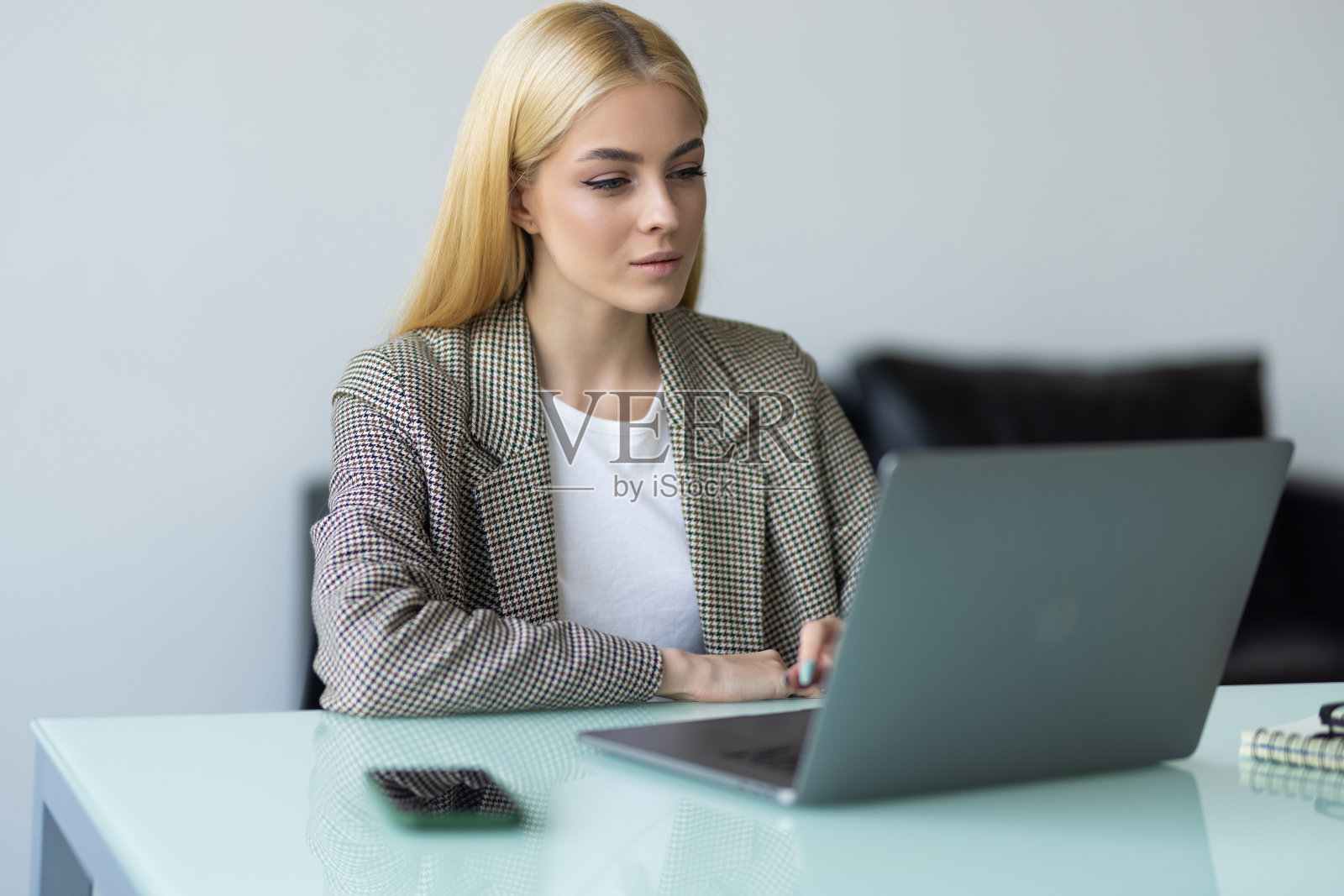 自由职业，在线学习，在线工作理念。年轻女性办公室职员坐在笔记本电脑和笔记在电话会议或视频电话与同事在办公室。照片摄影图片