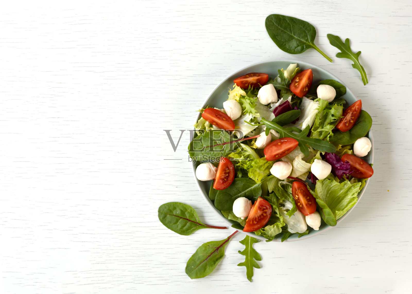 含生菜，菠菜，芝麻菜，马苏里拉奶酪和樱桃番茄的健康沙拉。全国沙拉月概念。照片摄影图片