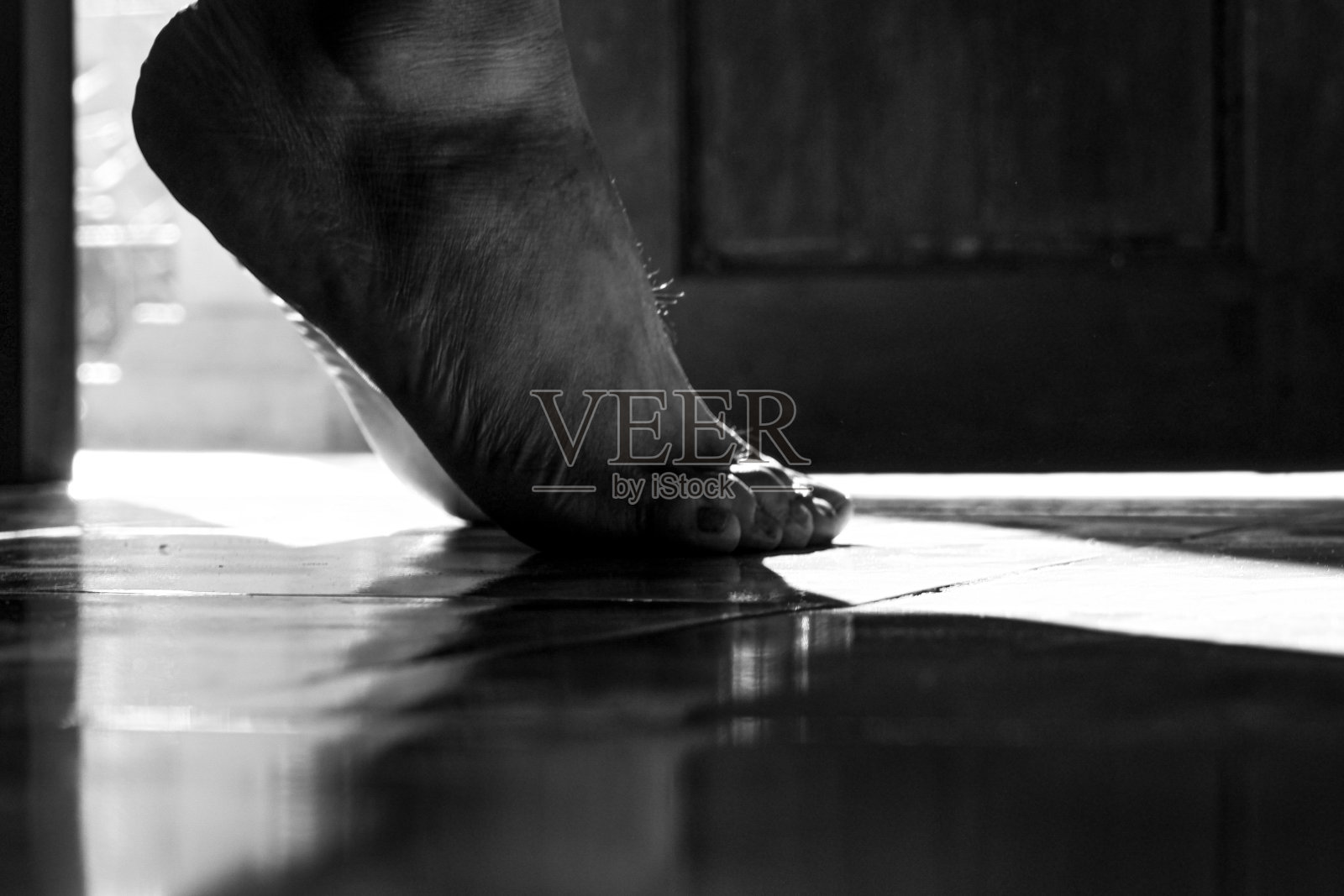 一双脚踮着脚尖站在门口，面向外面。照片摄影图片