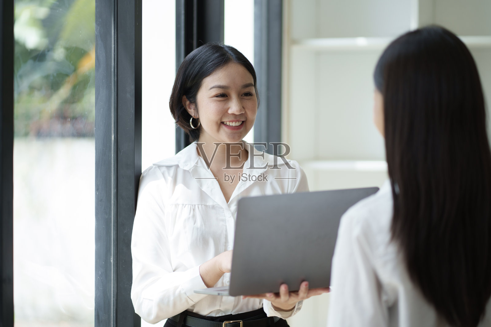 两个专业聪明的亚洲女商人在办公室里一起工作，从笔记本电脑上讨论信息。照片摄影图片