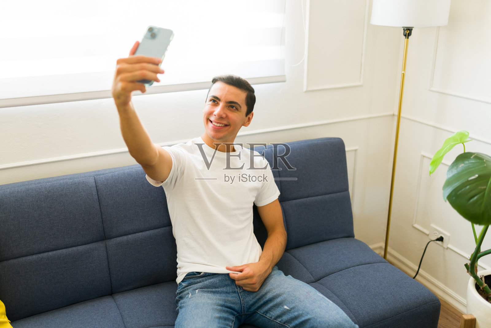 一名微笑的男子在自拍中展示他设计的模拟t恤照片摄影图片