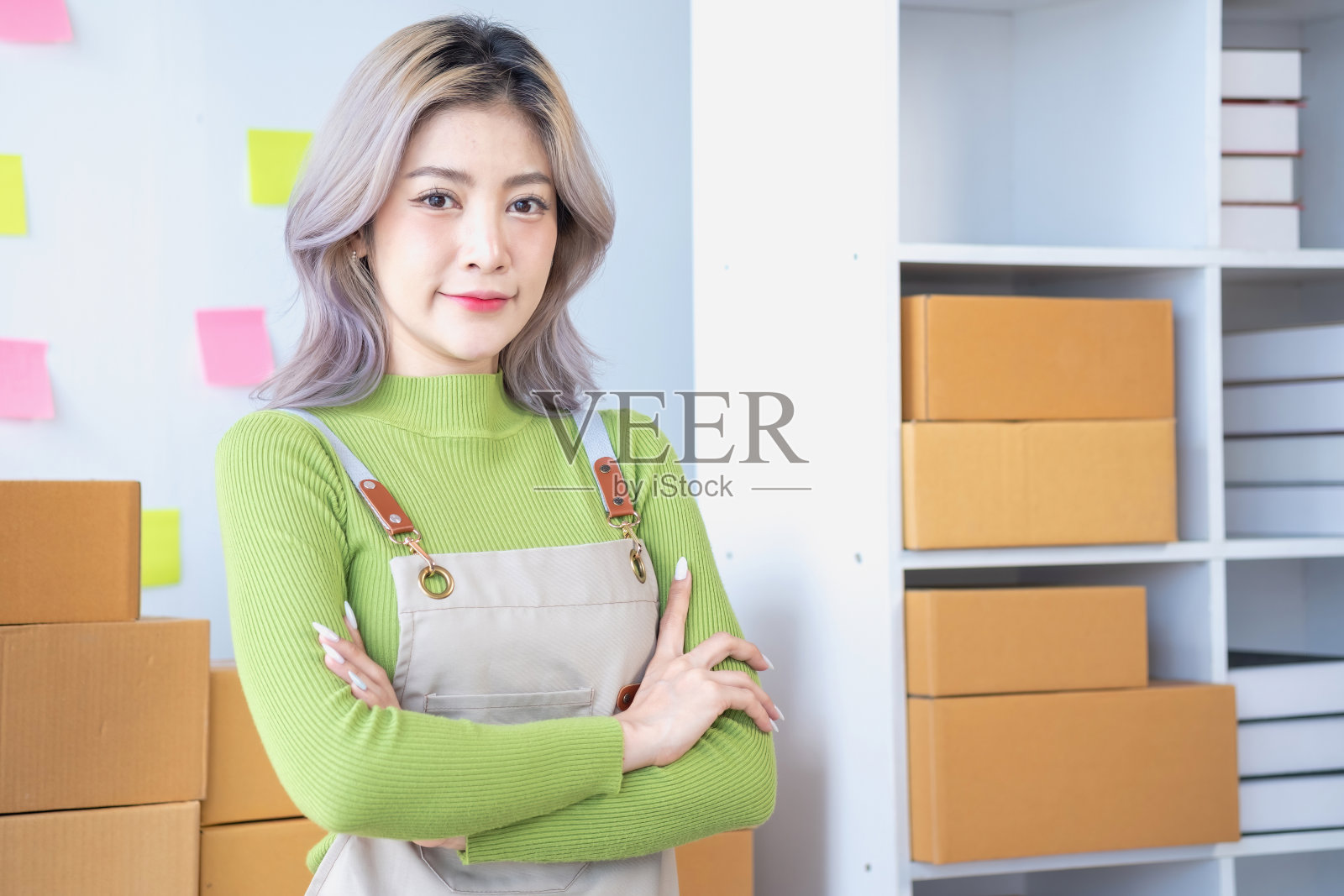 小企业主中小企业，微笑亚洲年轻女子，女孩老板自信地站着，双臂交叉准备订单发送给客户包装盒交付，在家在线工作，电子商务。照片摄影图片