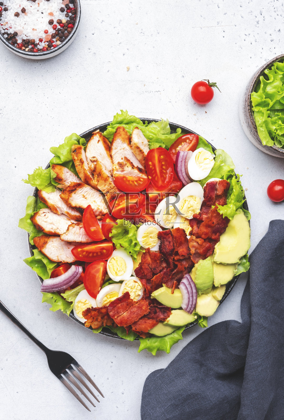 传统的科布沙拉，有鸡柳，西红柿，鸡蛋，培根，鳄梨和生菜，灰色桌面背景，俯视图。美式菜肴照片摄影图片