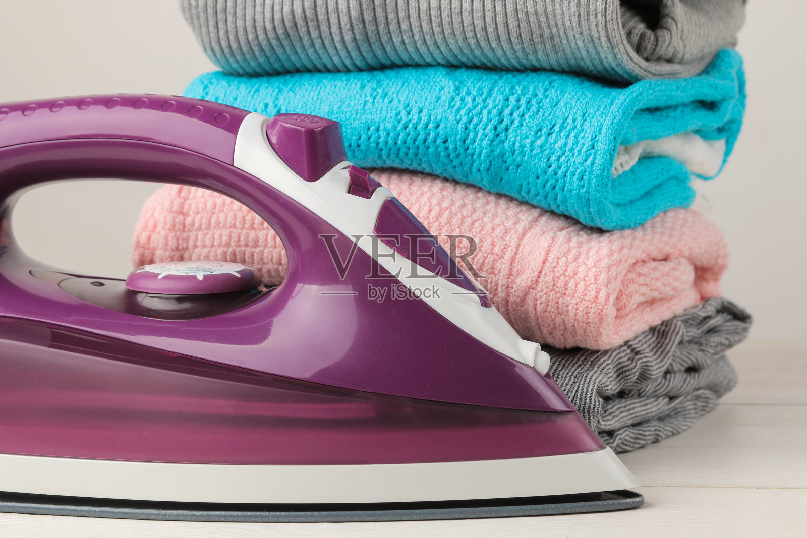 熨斗和一堆白色背景上的彩色衣服。衣物洗净后熨烫。照片摄影图片